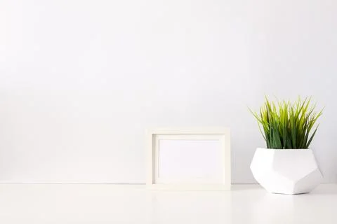 Desk on a white empty wall background with green grass in a geometric pot Stock Photos