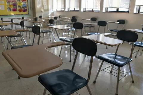 Desks in empty dark high, middle, or elementary school classroom with light Stock Photos