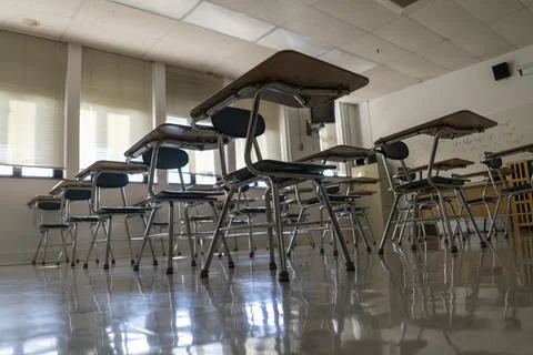 Desks in empty dark high, middle, or elementary school classroom with light Stock Photos