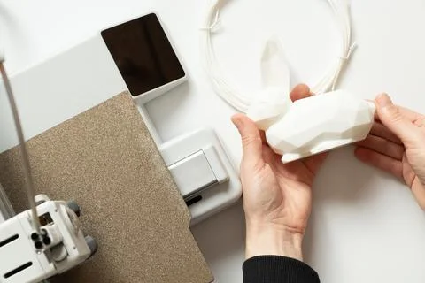 A desktop 3D printer and a white low-poly bunny on the printer, along with .. Stock Photos