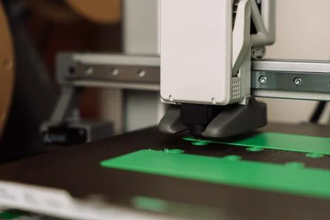 Desktop 3D printer creating green plastic parts on build plate in close-up view Foto stock