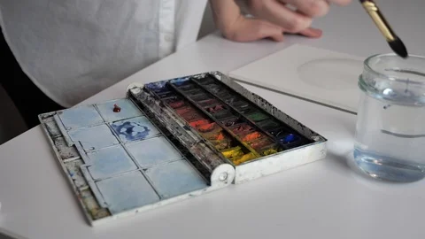 Desktop by artist. Preparing to draw, he wets the brush in water and mixes water Stock Footage 126097688