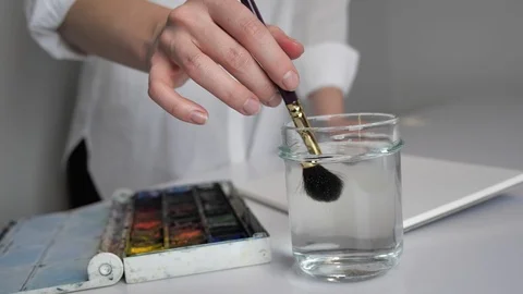 Desktop by artist. Preparing to draw, he wets the brush in water and mixes Video stock 126153541