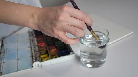 Desktop by artist. Preparing to draw, he wets the brush in water and mixes Stock Footage 127023488