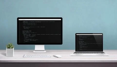 Desktop computer and laptop on work desk with programming editor on display.  Stock Photos