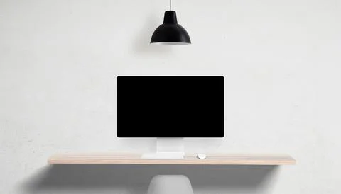 Desktop computer with blank screen on clean desk, overhead lamp and empty Stock Photos