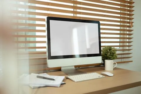 A desktop computer with blank screen on desk with natural light streaming in Stock Photos