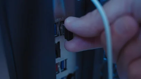 Desktop computer close up as hand inserts small flash drive in dark room Video stock 334734308