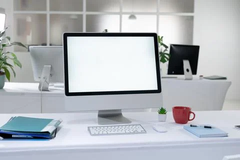 Desktop computer with illuminated screen and cup at workstation in abandoned Stock Photos