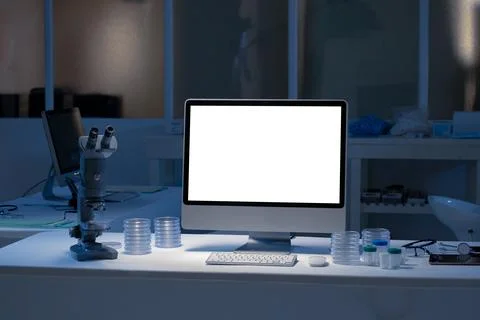 Desktop computer with illuminated screen at workstation in medical laboratory Foto stock