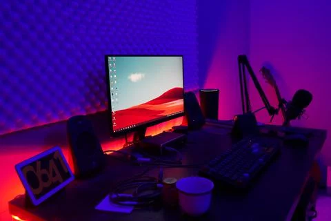 A desktop computer setup with colorful lights behind desk Foto stock