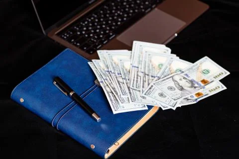 Desktop flatlay: laptop, notebook, pen and cash money lying on black backgrou Foto stock
