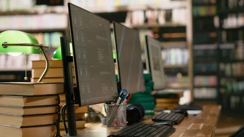 Desktop monitors with blue screen and AI chatbot in library workspace Stock Photos