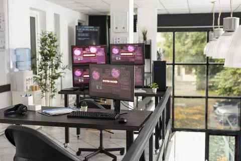 Desktop monitors show system error warnings in empty office workspace Foto stock