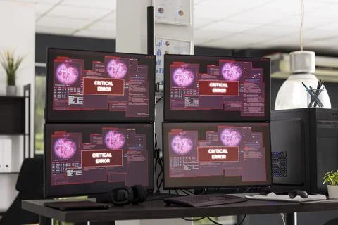 Desktop monitors show system error warnings in empty office workspace Stock Photos