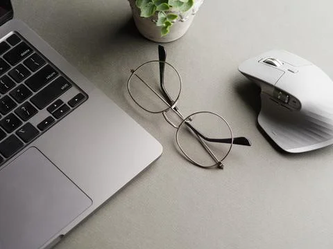 On the desktop, there is a laptop, glasses, a computer mouse and a decor - a  Stock Photos