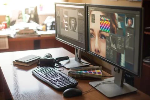 Desktop with two monitors, a keyboard, a camera, a diary, a palette for a des Stock Photos