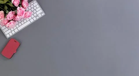 Desktop workspace with computer keyboard, smartphone and lovely pink rose flo Stock Photos