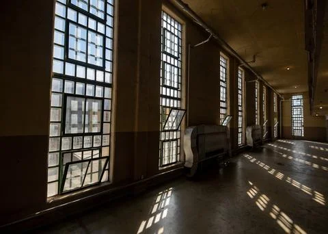 Desolate corridor with geometric light beams through high windows Stock Photos