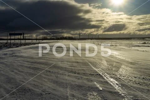 Desolate empty, icy road and harsh sunlight Stock Photos