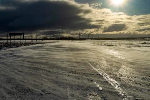 Desolate empty, icy road and harsh sunlight Stock Photos