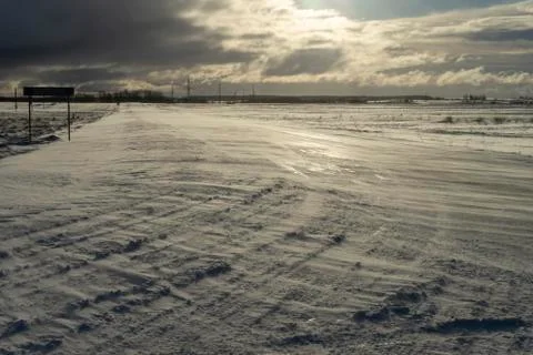 Desolate empty, icy road and harsh sunlight Stock Photos