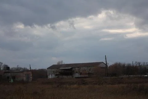 Desolate old agricultural hangar under heavy storm clouds Stock Photos