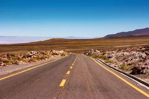 Desolate road between the mountains and the arid desert of Atacama Stock Photos