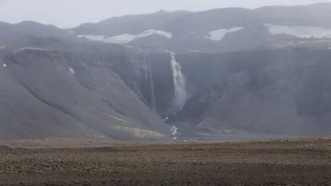 Desolate volcanic landscape with a waterfall flowing from a melting glacier Stock Footage 344058736