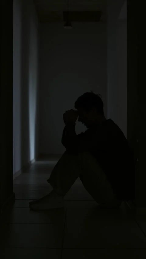Despair and sadness young man praying alone in dark hallway feeling loss Stock Footage 313879451