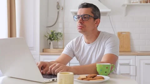 Despair man sitting at table in kitchen working on laptop angrily yelling at Vidéo 291271046