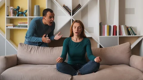 Desperate girlfriend meditating sitting on sofa while boyfriend screams  Video stock 136940026