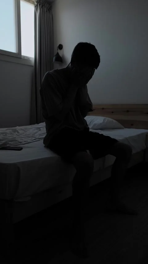 Desperate man covers face while sitting alone during personal crisis, vertical Видео 346243665