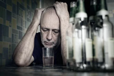 Desperate man falling into depression and becoming alcoholic Stockfoto's