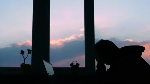 Desperate man at his desk, depression. Silhouette of a man tired at sunset Stock Footage 153632229