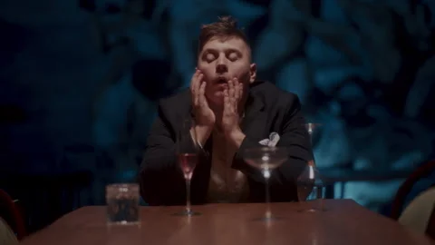 A desperate man sitting alone at the table and drinking 스톡 동영상 258334511