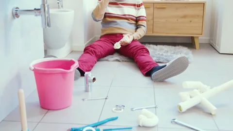 Desperate man sitting on the bathroom floor and calling a plumber Stock Footage 297856183