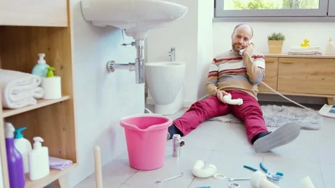 Desperate man sitting on the bathroom floor and calling a plumber Stock Footage 297856227