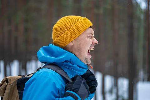 Desperate man in winter forest screaming, expressing distress, fear, and Stock Photos