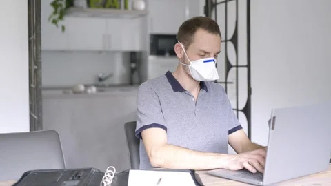 Desperate masked man in quarantine working on laptop and taking notes Stock Footage 126774776