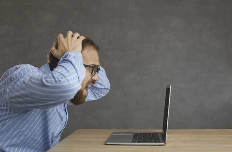 Desperate office worker looking at error message on screen of his laptop Foto stock