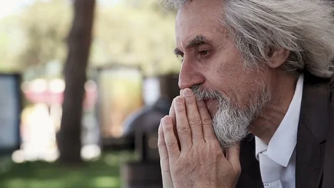 Desperate old man in a suit with a beard prays, mutters and cries in the alley 库存影片 96546950