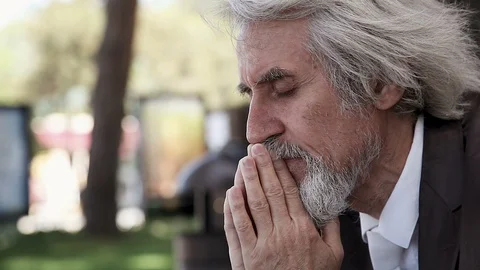 Desperate upset old man with a beard prays, mutters and cries in the Park Stock-Footage 96545464