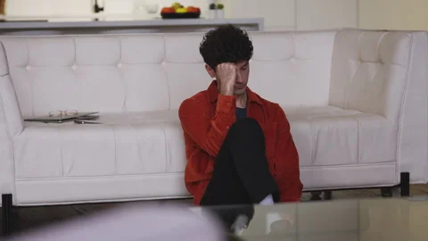 Desperate young man thinking about family problems while sitting on the floor Stock Footage 341017025