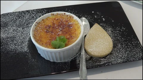 Dessert of creme brule with shortbread biscuit on black plate Stock Footage 42283649