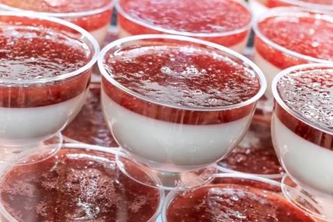 Dessert pudding with strawberry jam in plastic sockets on the counter Stock Photos