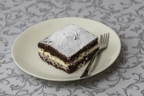 Dessert in a square shape interlaced with whipped cream and decorated with .. Stock Photos