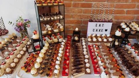 Dessert table with assorted cupcakes, mini cakes, chocolate treats, and fresh Stock Photos