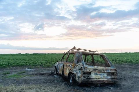 Destroyed and burnt car in the fields, accident or war concept Stock Photos