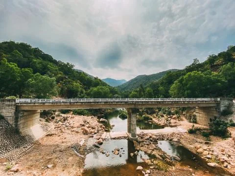 The destroyed bridge over the mountain river. Concrete bridge collapsed after Stock Photos
